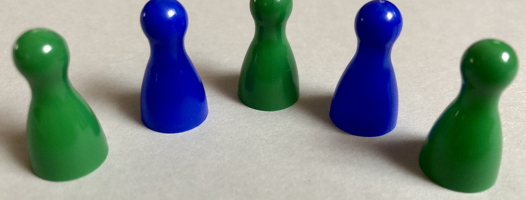 Fünf Spielfiguren in grüner und blauer Farbe, angeordnet in einem Halbkreis.
