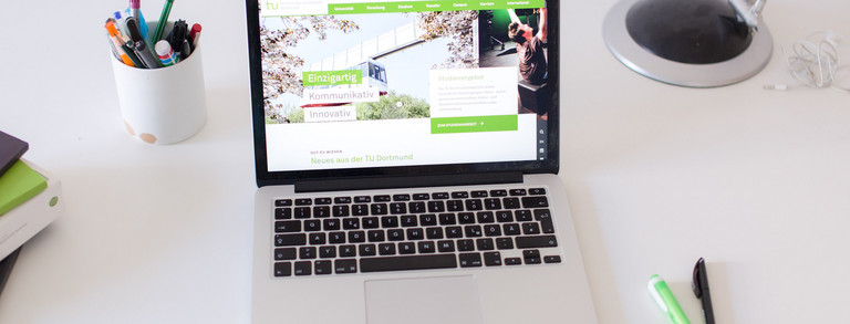 Arbeitsplatz mit Laptop Arbeitsplatz am Schreibtisch, mit eingeschaltetem Laptop und Stiften.