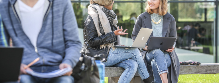 Two students in conversation Two students sitting on a bench are talking to each other