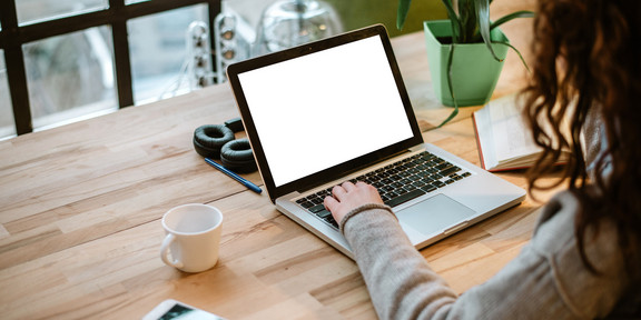 desk over-the-shoulder shot of person sitting at laptop